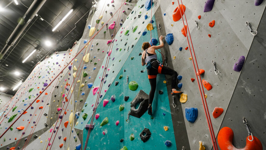 A climber halfway up the wall climbing indoors
