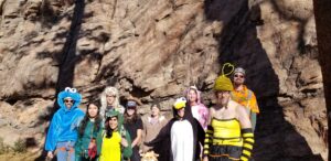 Group photo at the Hauntin' Staunton climbing day. Everyone is in costumes smiling while standing in front of a rock wall.